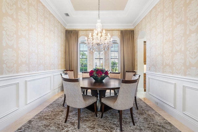 dining room featuring a raised ceiling, ornamental molding, and a notable chandelier