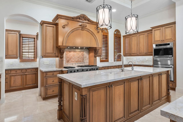 kitchen featuring decorative backsplash, ornamental molding, stainless steel range, pendant lighting, and an island with sink