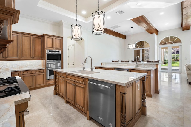 kitchen featuring sink, hanging light fixtures, backsplash, a kitchen island with sink, and appliances with stainless steel finishes