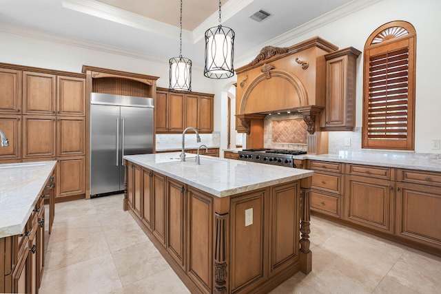 kitchen with a center island with sink, crown molding, hanging light fixtures, appliances with stainless steel finishes, and light stone counters