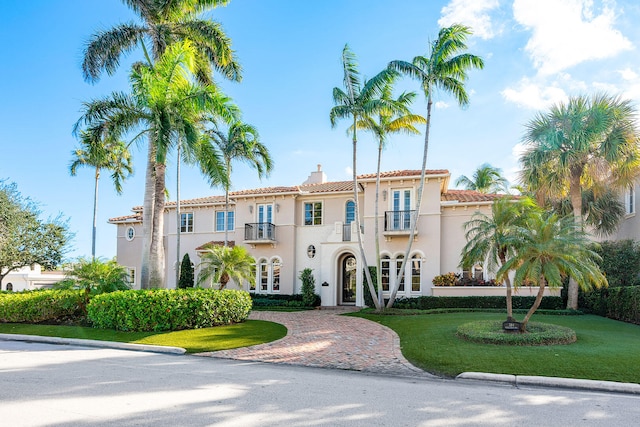 mediterranean / spanish-style house with a balcony, cooling unit, and a front yard