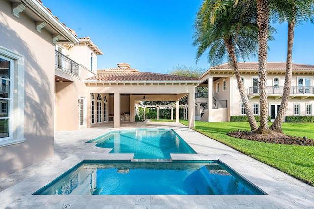 rear view of house featuring a yard, a balcony, a patio area, and a pool with hot tub