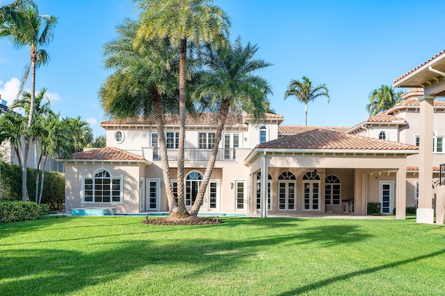 back of house with a lawn, ceiling fan, and a balcony