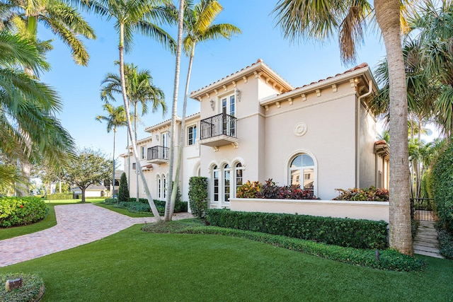 view of front of house with a balcony and a front lawn