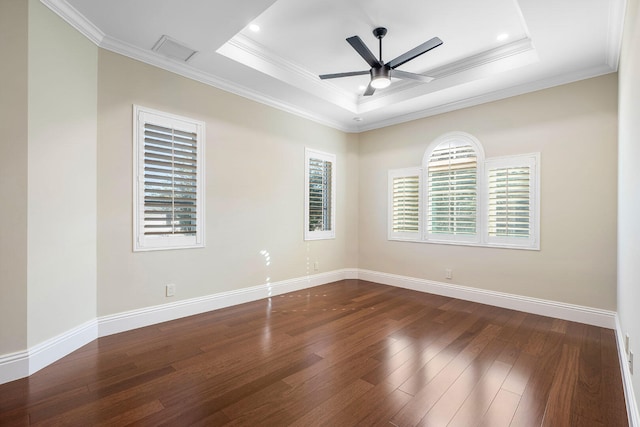 spare room featuring dark hardwood / wood-style floors, ceiling fan, ornamental molding, and a tray ceiling