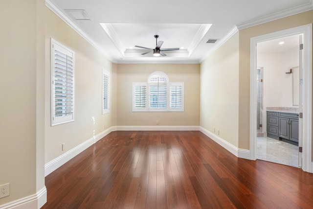 empty room featuring a raised ceiling, ceiling fan, dark wood-type flooring, and ornamental molding