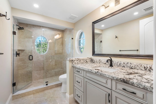 bathroom featuring tile patterned floors, vanity, a shower with shower door, and toilet