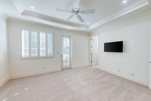 carpeted empty room featuring a raised ceiling and crown molding