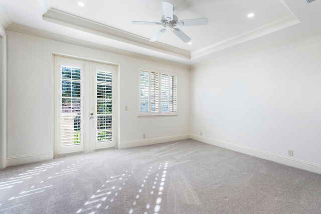 empty room with french doors, light colored carpet, a raised ceiling, and crown molding