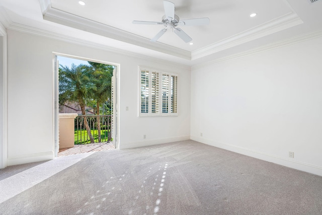 carpeted empty room with a tray ceiling, ceiling fan, and ornamental molding