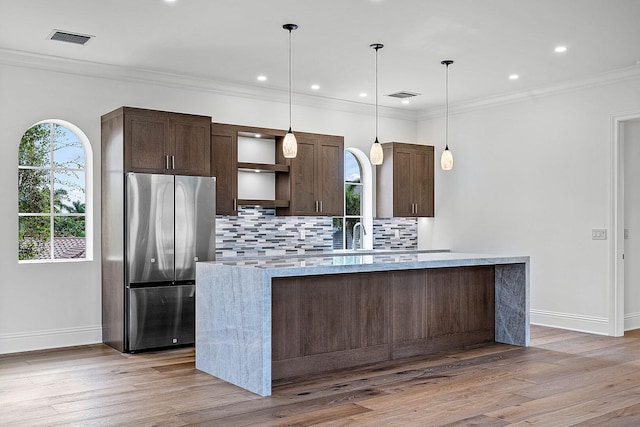 kitchen featuring stainless steel refrigerator, dark brown cabinetry, a center island, and light hardwood / wood-style floors