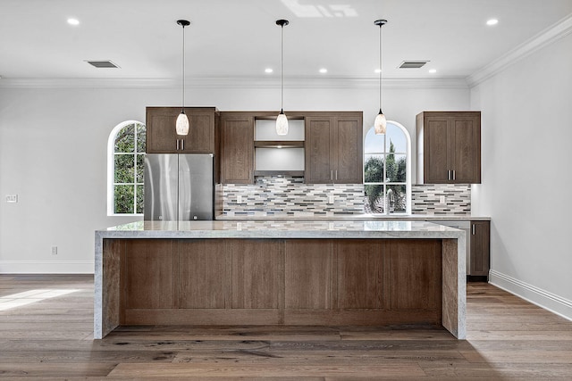 kitchen with decorative backsplash, a kitchen island, wood-type flooring, and stainless steel refrigerator