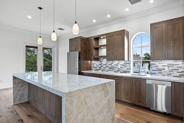 kitchen with light stone counters, a kitchen island, light wood-type flooring, and appliances with stainless steel finishes