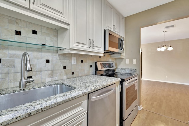 515 High Point Dr Unit B, Delray Beach, FL 33445 - kitchen featuring stainless steel appliances, a sink, light wood-style floors, decorative backsplash, and light stone counters