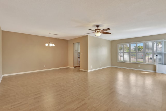 unfurnished room with a textured ceiling, light wood-type flooring, and ceiling fan with notable chandelier