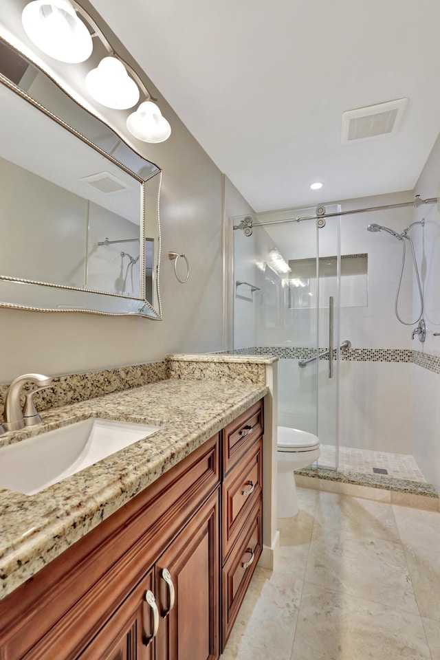 bathroom with vanity, toilet, and a shower with door