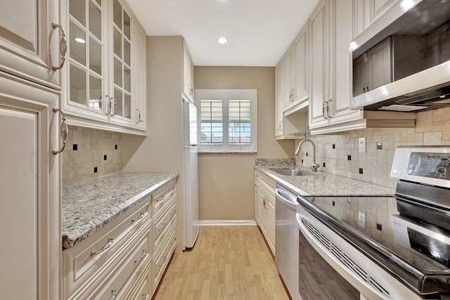 kitchen featuring sink, light hardwood / wood-style flooring, stainless steel appliances, and tasteful backsplash