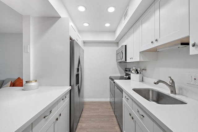 kitchen with white cabinets, light wood-type flooring, stainless steel appliances, and sink