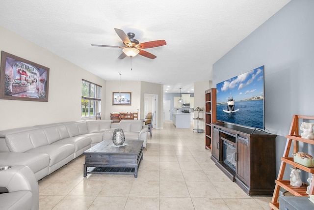 tiled living room with a textured ceiling and ceiling fan with notable chandelier