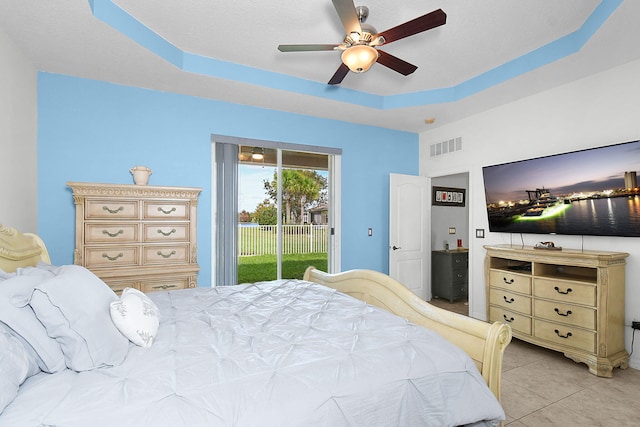 bedroom featuring access to outside, light tile patterned flooring, a tray ceiling, and ceiling fan