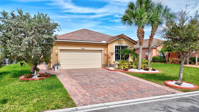 view of front of property featuring a front yard, cooling unit, and a garage