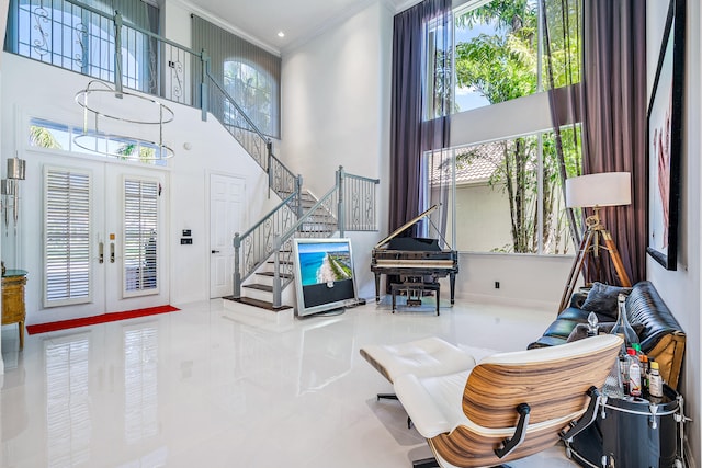 interior space with french doors, crown molding, and a towering ceiling