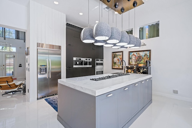 kitchen with gray cabinetry, stainless steel appliances, a center island, decorative light fixtures, and light tile patterned floors