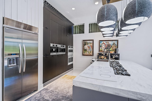 kitchen with sink, a textured ceiling, appliances with stainless steel finishes, and pendant lighting