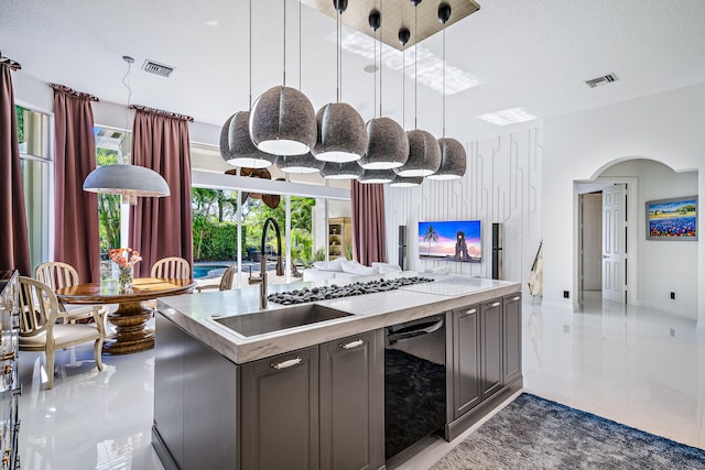 kitchen with black dishwasher, dark brown cabinets, sink, decorative light fixtures, and a textured ceiling