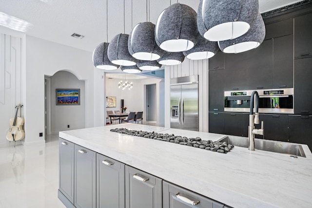 kitchen featuring light stone countertops, sink, a textured ceiling, stainless steel appliances, and a chandelier