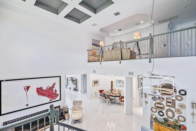 living room featuring beam ceiling, ornamental molding, a towering ceiling, a notable chandelier, and coffered ceiling