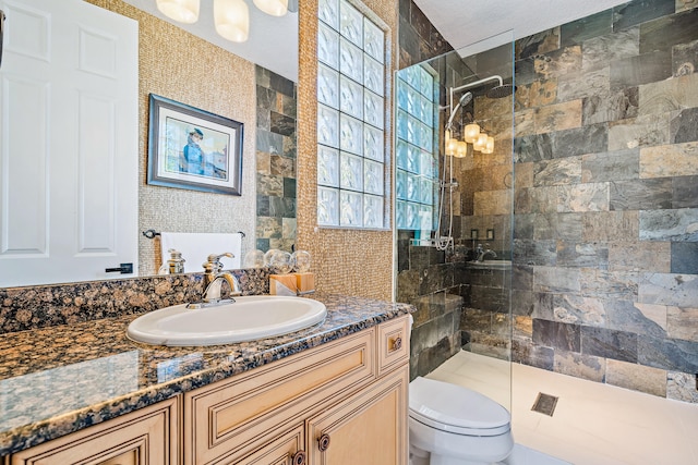 bathroom with vanity, toilet, and tiled shower