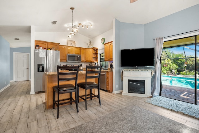 kitchen featuring a breakfast bar, a center island, lofted ceiling, light wood-type flooring, and appliances with stainless steel finishes