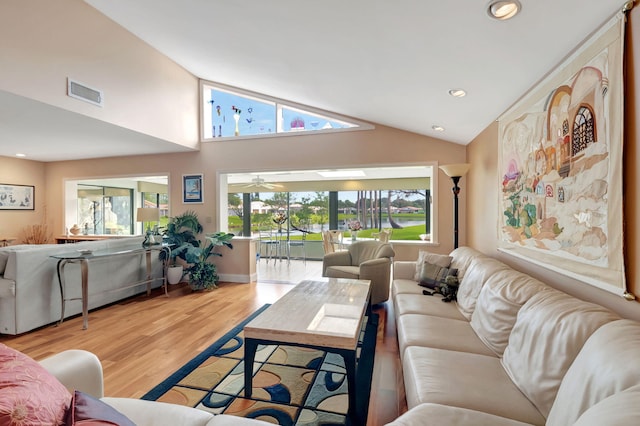 living room with high vaulted ceiling, a wealth of natural light, and light wood-type flooring