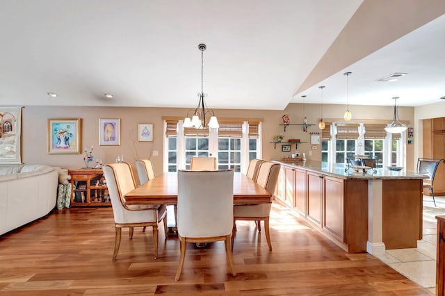 dining space with an inviting chandelier, light hardwood / wood-style flooring, lofted ceiling, and a wealth of natural light