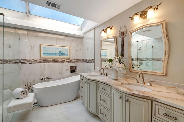 bathroom with vanity, a skylight, shower with separate bathtub, and tile walls