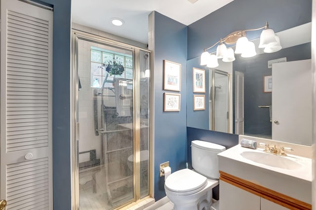 bathroom featuring vanity, a shower with shower door, and toilet