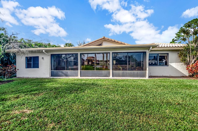 rear view of property with a yard and a sunroom