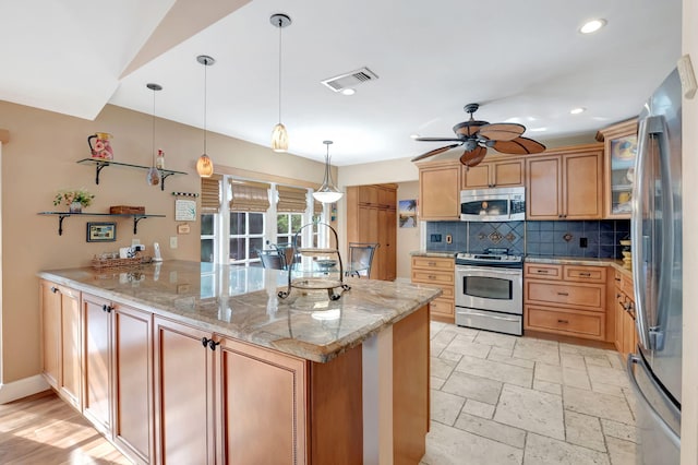 kitchen with kitchen peninsula, light stone countertops, pendant lighting, appliances with stainless steel finishes, and ceiling fan