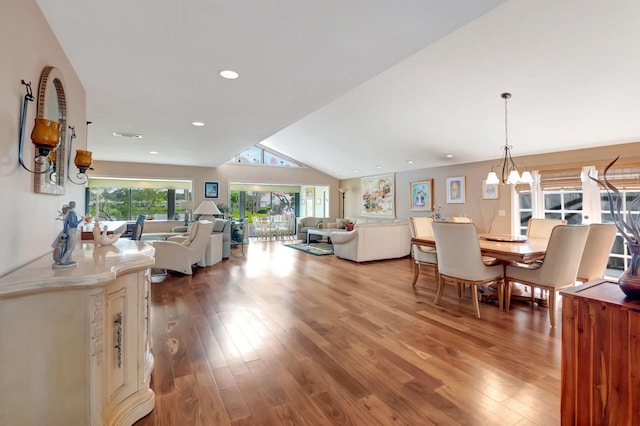 living room with hardwood / wood-style flooring, vaulted ceiling, and an inviting chandelier