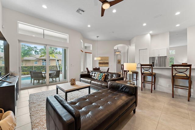 living area with a wealth of natural light, visible vents, ceiling fan, and arched walkways