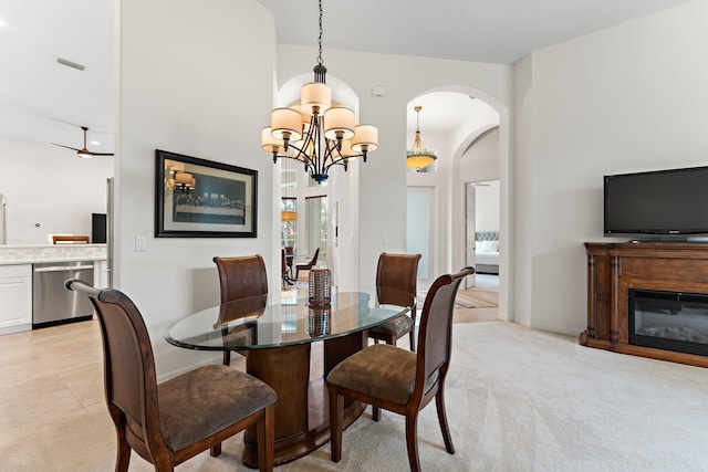 dining room with arched walkways, an inviting chandelier, light colored carpet, a glass covered fireplace, and visible vents