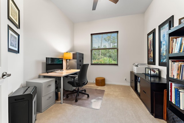 office area featuring a ceiling fan, baseboards, and light carpet