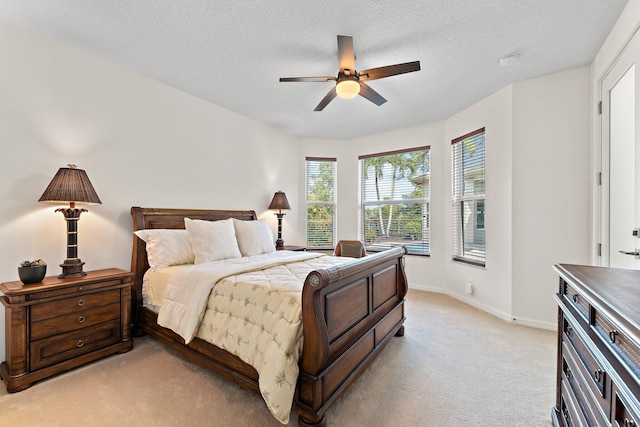 bedroom with a textured ceiling, light colored carpet, and ceiling fan