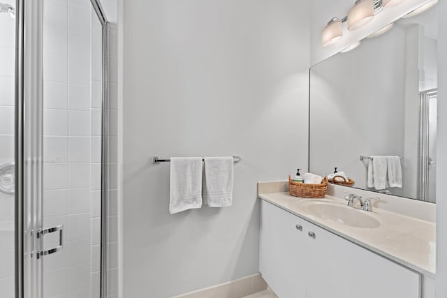 bathroom with baseboards, a shower stall, and vanity