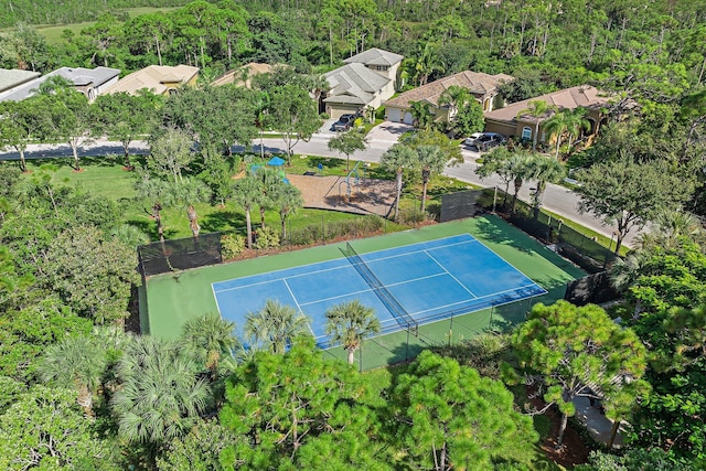 view of tennis court with a forest view and fence