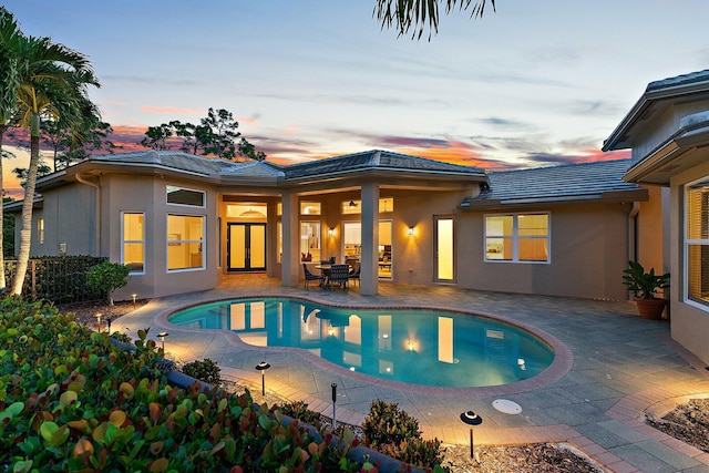 back of property with stucco siding, an outdoor pool, a patio, and a tile roof