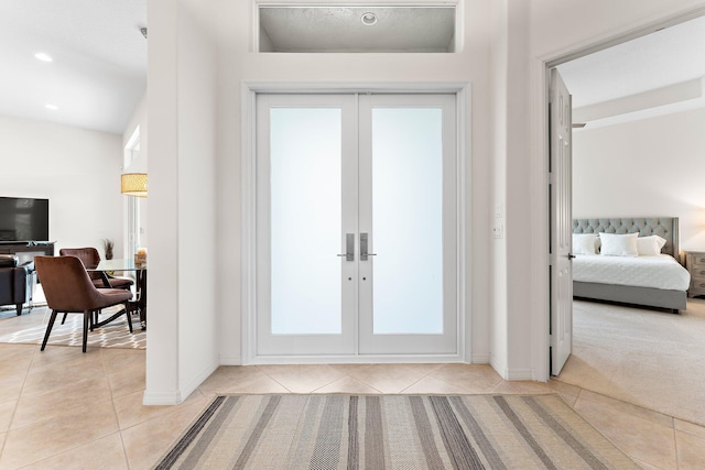 entryway featuring light tile patterned floors, light colored carpet, french doors, and baseboards
