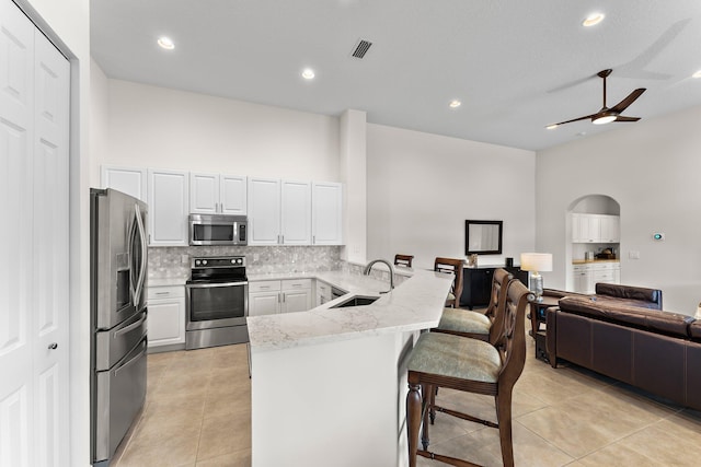 kitchen with kitchen peninsula, a breakfast bar area, white cabinetry, sink, and stainless steel appliances