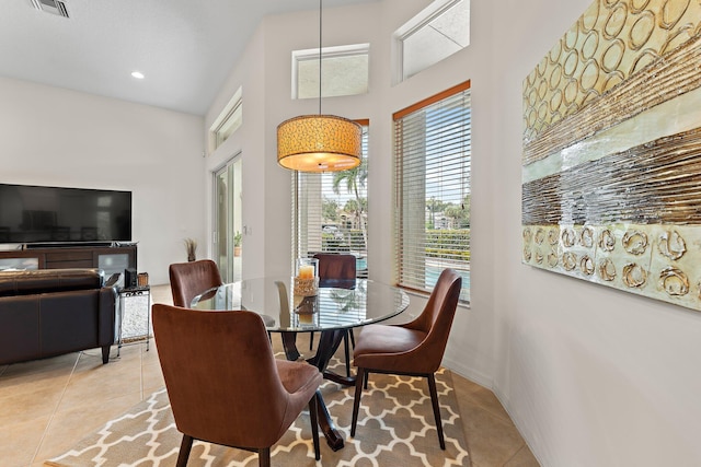 dining area featuring light tile patterned floors, a towering ceiling, visible vents, and a wealth of natural light